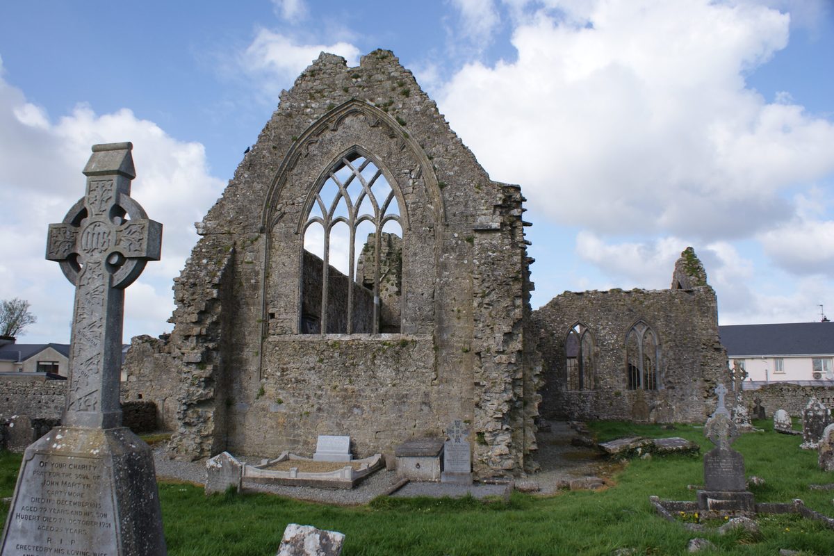 The gothic window of a ruined stone abbey in the Irish countryside